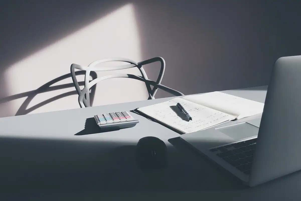 Calculator și caiet așezate pe o masă din lemn, pregătite pentru calculul pretențiilor salariale