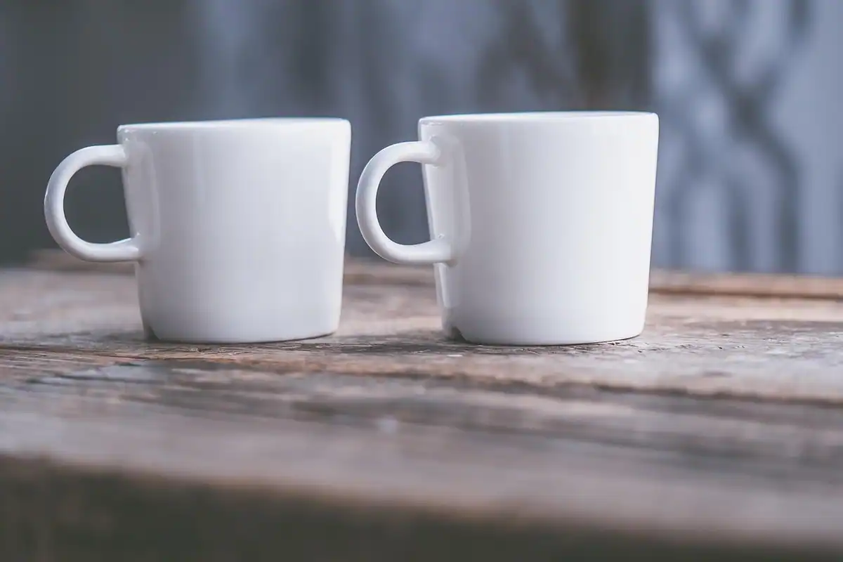 Două căni de cafea pe o masă de birou, imagine despre discuția calmă cu un coleg după un conflict