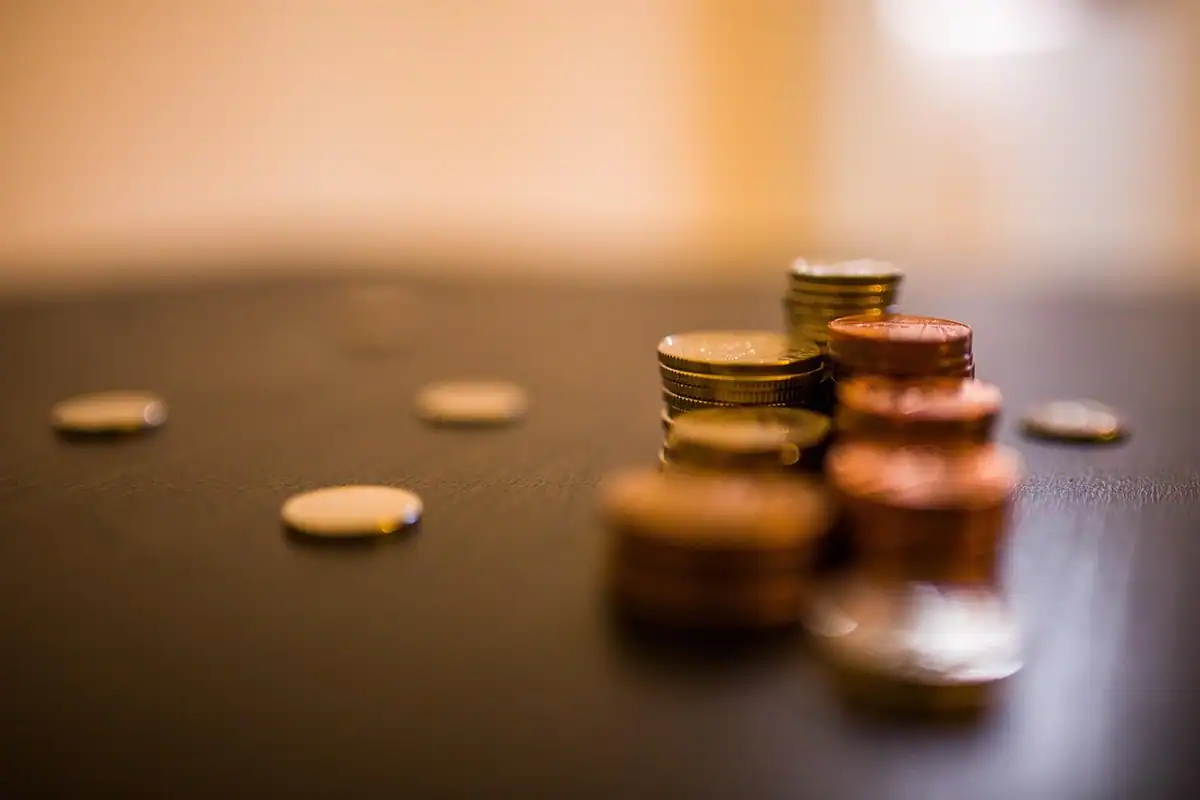 Borcan cu monede pe o masă din lemn, imagine despre economiile puse deoparte pentru reconversie
