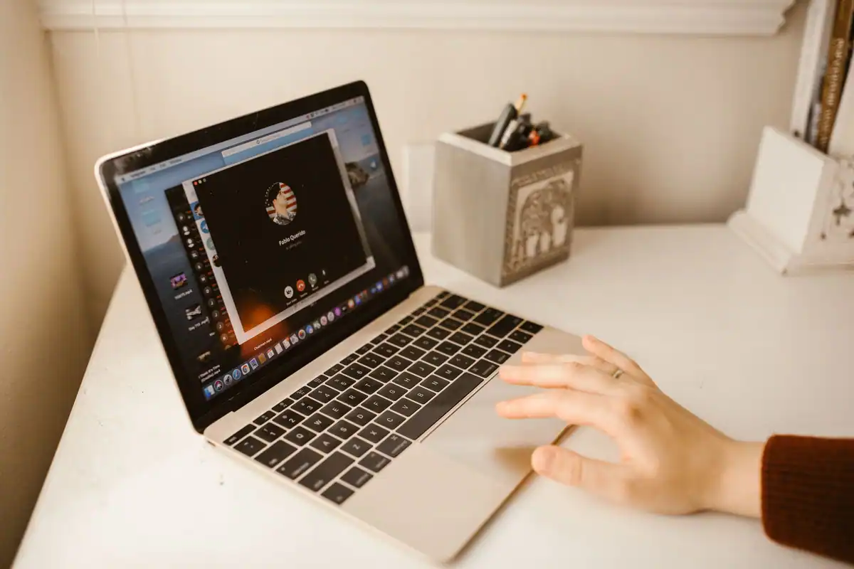 Persoană care participă la un apel video pe laptop, acasă la birou