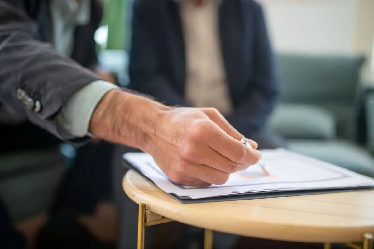 Profesionist care scrie pe un document în timpul unei întâlniri de afaceri