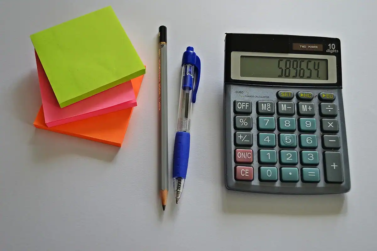 Contabil lângă calculator și hârtii pe birou, imagine despre alegerea între PFA și SRL