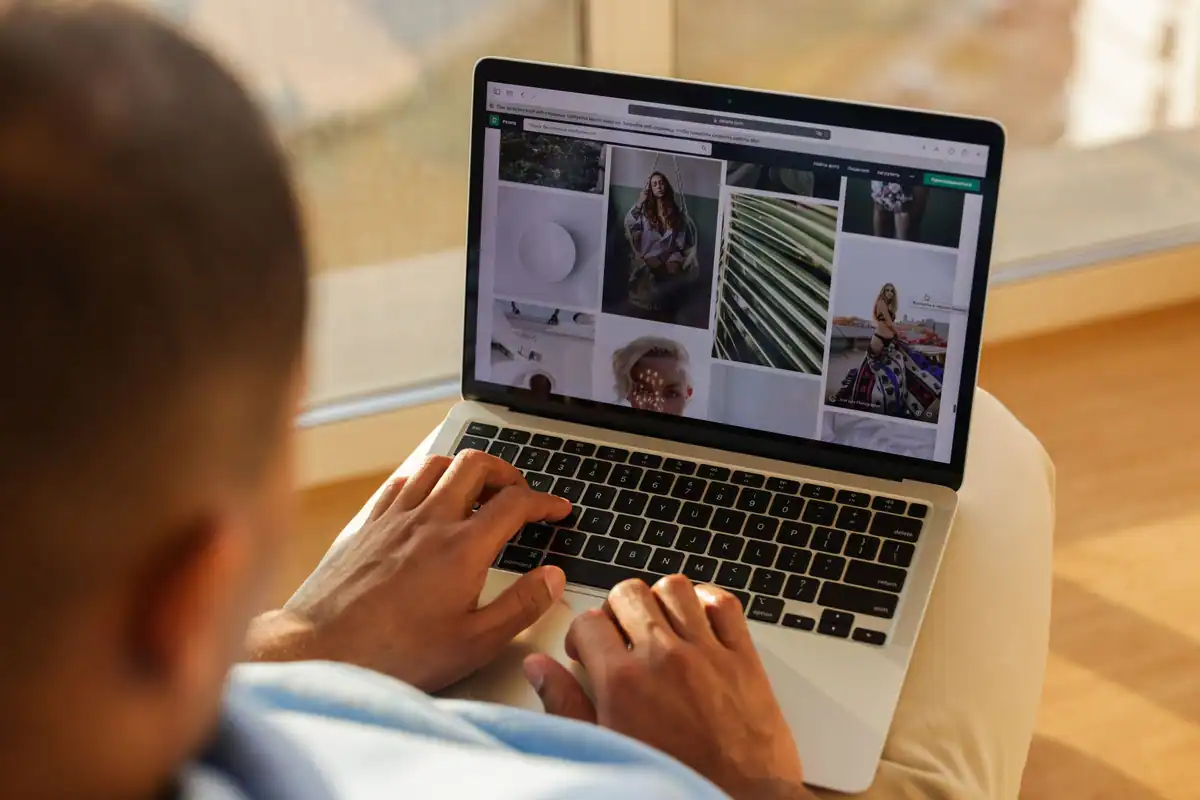 Persoană care răsfoiește pe laptop un portofoliu de fotografie