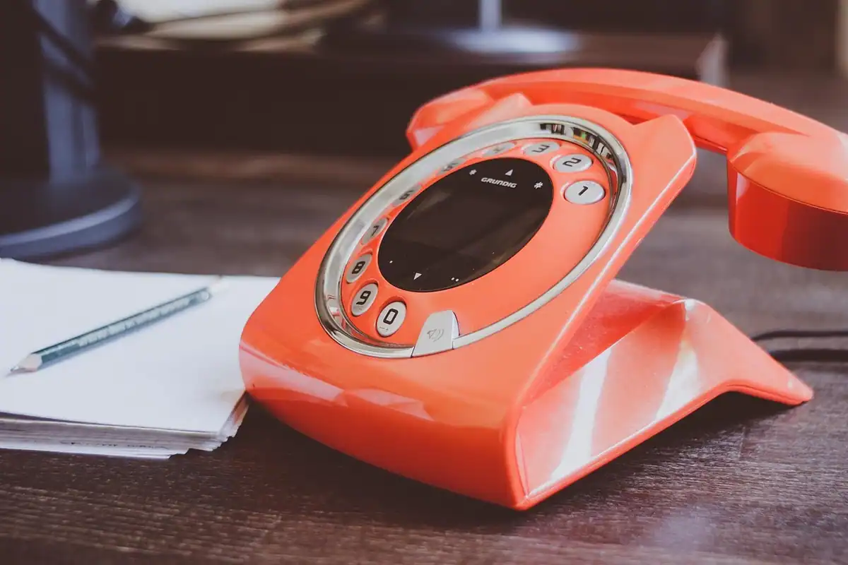Telefon fix pe birou lângă un bloc de notițe, pregătit pentru discuția cu persoanele de referință